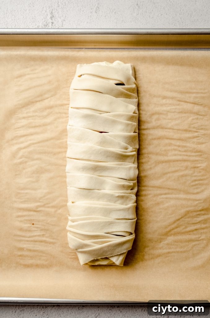 Raspberry Cream Cheese Danish Recipe 12 A braided pastry on a baking sheet lined with parchment paper.