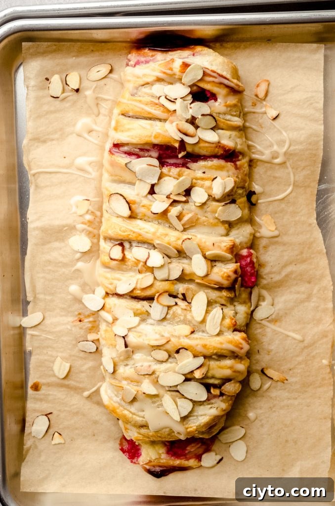 Raspberry Cream Cheese Danish Recipe 16 A pastry braid filled with raspberries and cream cheese with toasted almonds and an icing on it.