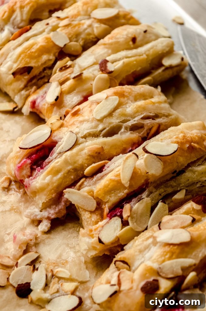 Raspberry Cream Cheese Danish Recipe 17 A pastry braid filled with raspberries and cream cheese with toasted almonds and an icing on it sliced into portions.