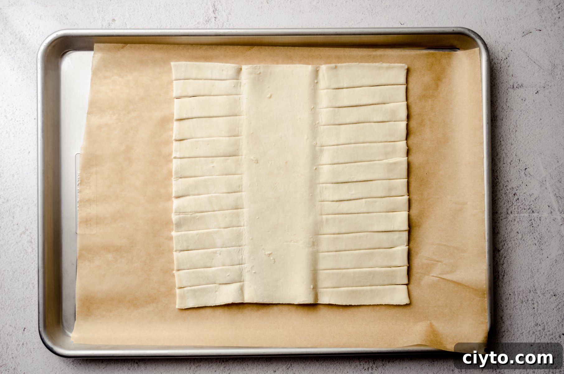 Raspberry Cream Cheese Danish Recipe 7 A rectangle of puff pastry dough on a baking sheet lined with parchment paper.