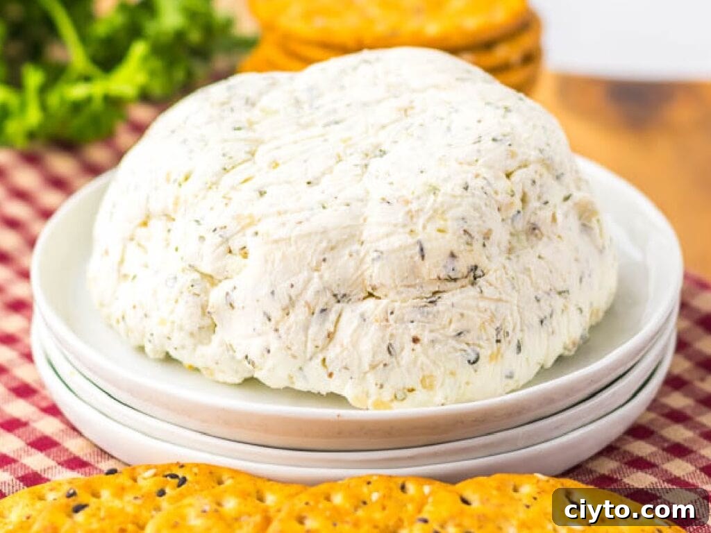 Creamy Homemade Boursin-Style Garlic and Herb Cheese Spread 6 Mound of homemade Boursin garlic and herb cheese spread on a white plate, surrounded by crackers on a checkered cloth background.