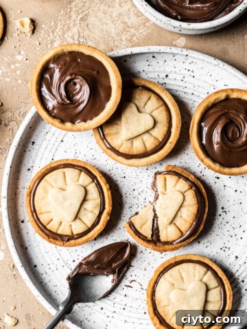 Nutella filled biscuits on a white speckled ceramic plate.