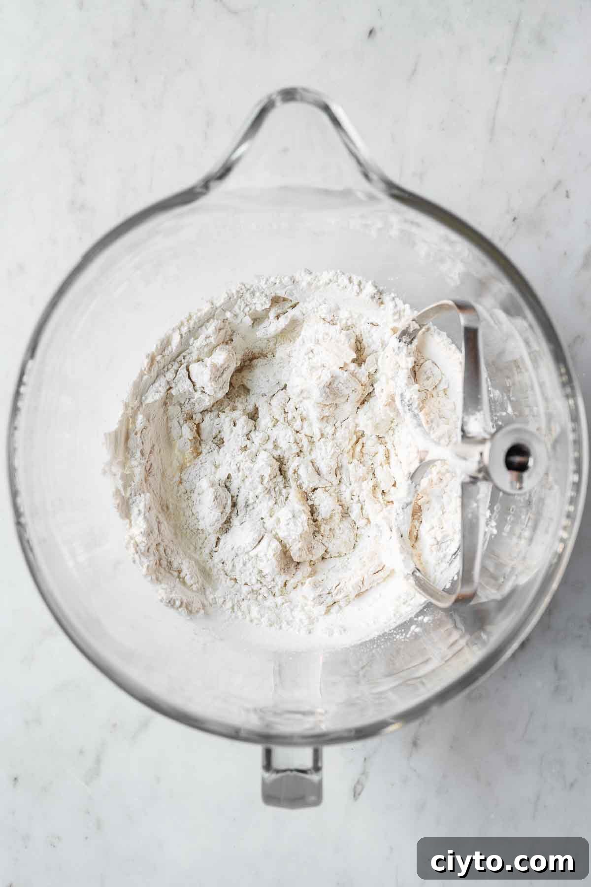 Dry ingredients added to wet in a glass mixing bowl.