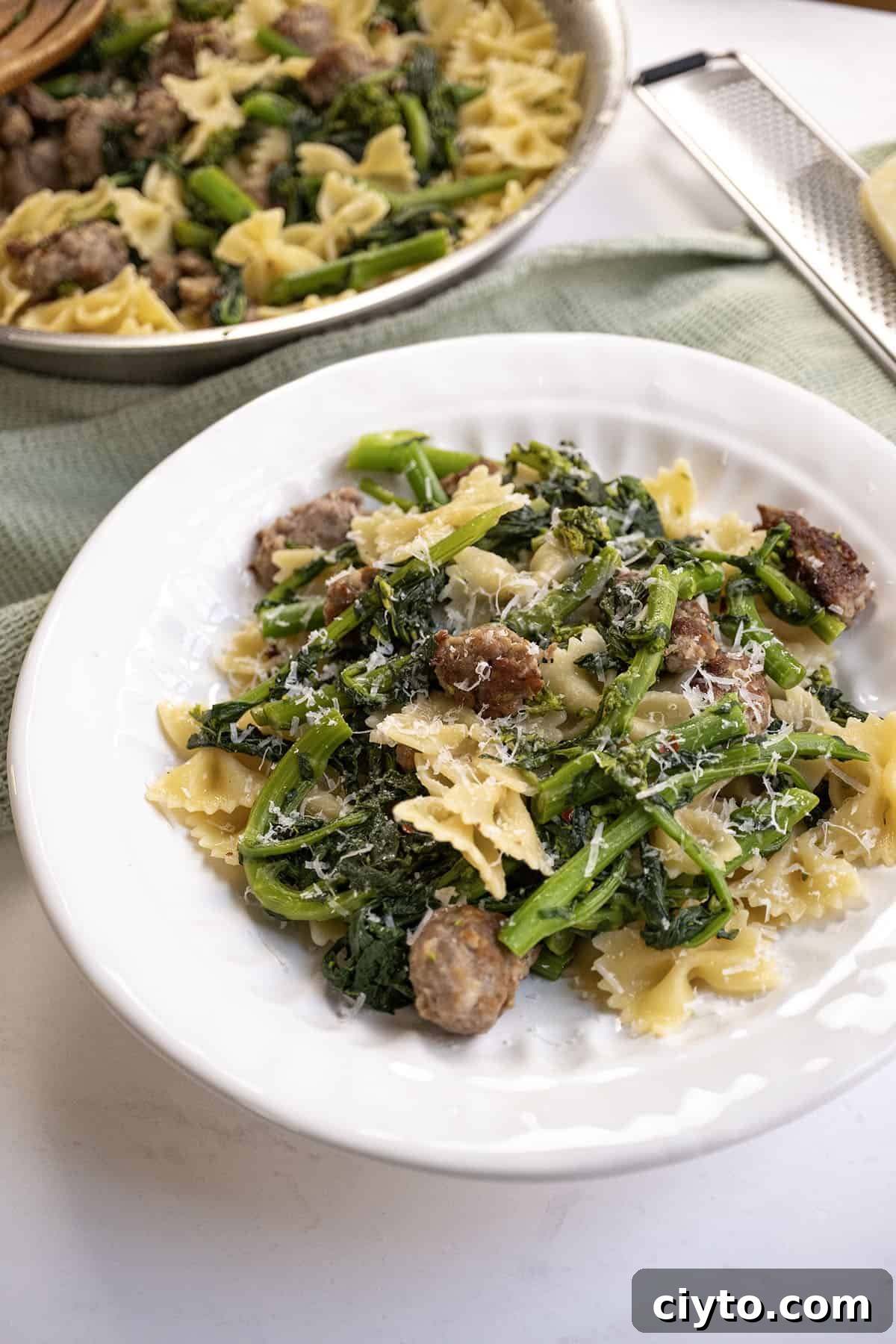 Garlicky Sausage and Broccoli Rabe Pasta 2 Farfalle with sausage and broccoli rabe, topped with parmesan on a plate.