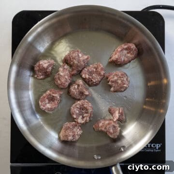 Garlicky Sausage and Broccoli Rabe Pasta 6 Pieces of ground sausage searing on a pan.
