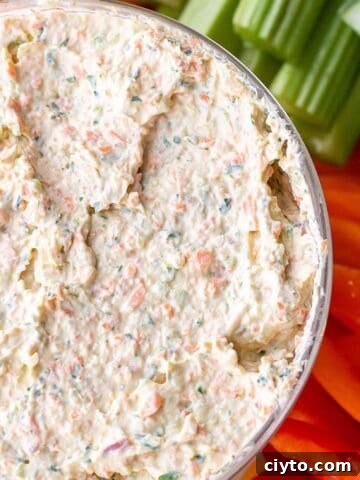 A bowl of a veggie cream cheese mix with fresh cut veggies.