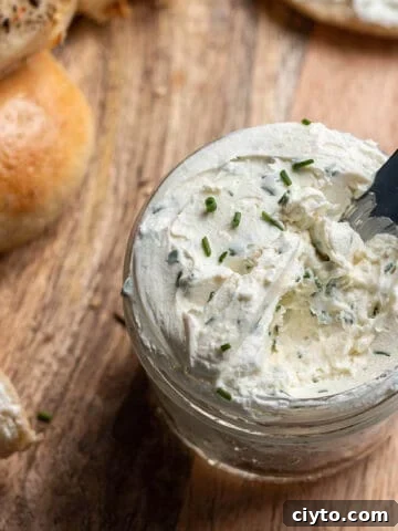 A wooden board with a jar of cream cheese and knife.