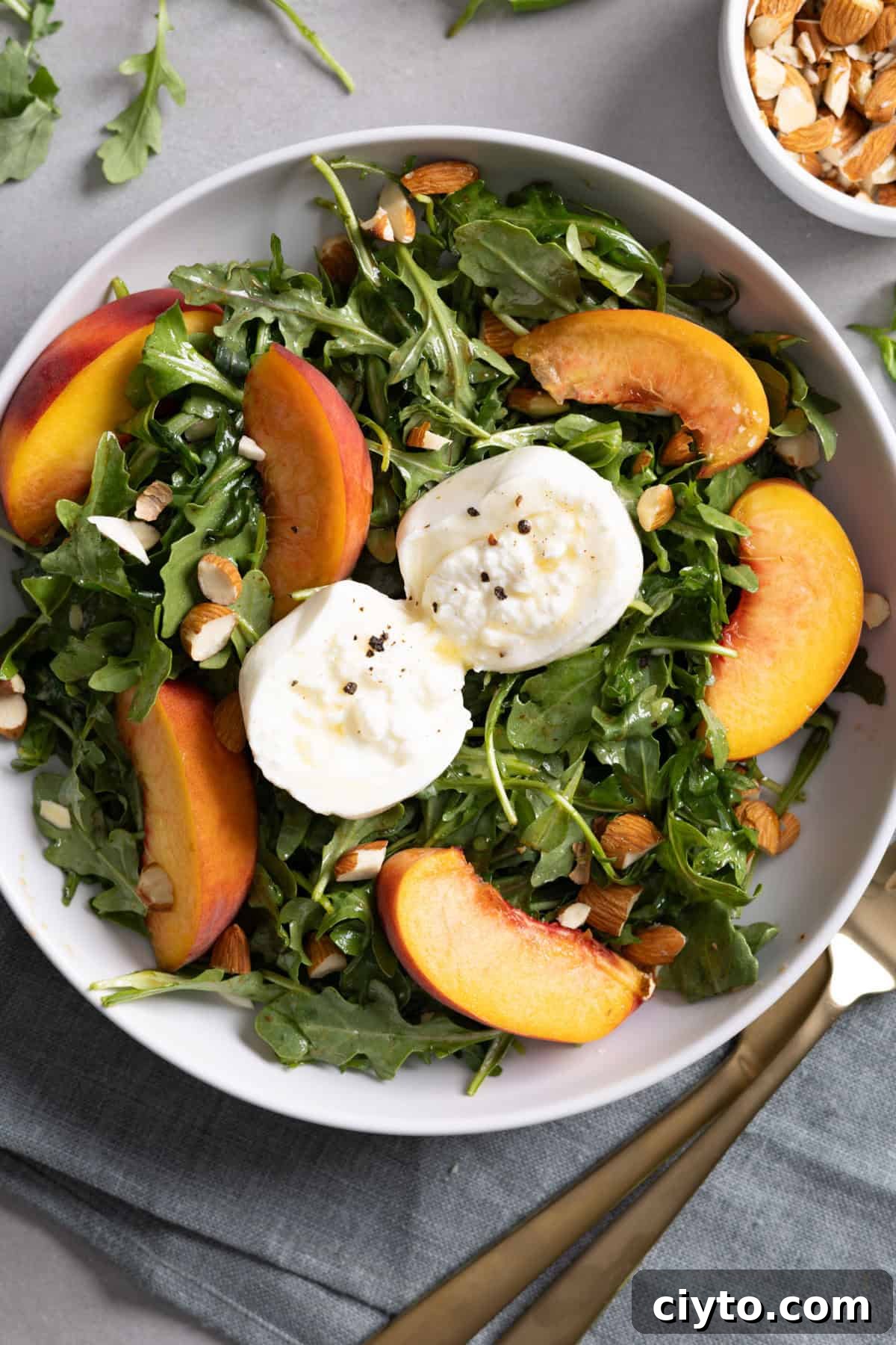 Arugula and Burrata Salad Recipe with Lemon Vinaigrette 11 Close up of a serving of arugula burrata salad with peaches and almonds.