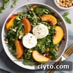 Close up of a serving of arugula burrata salad with peaches and almonds.
