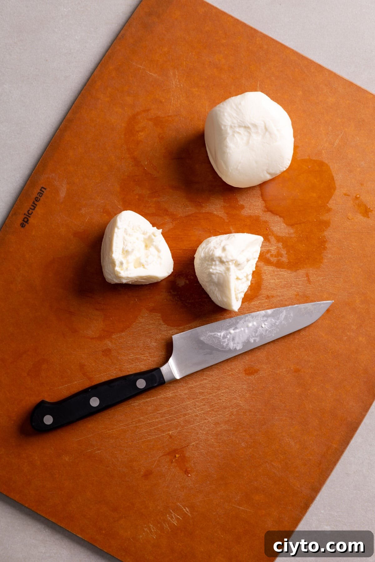 Arugula and Burrata Salad Recipe with Lemon Vinaigrette 7 Burrata cheese getting sliced on a cutting board.