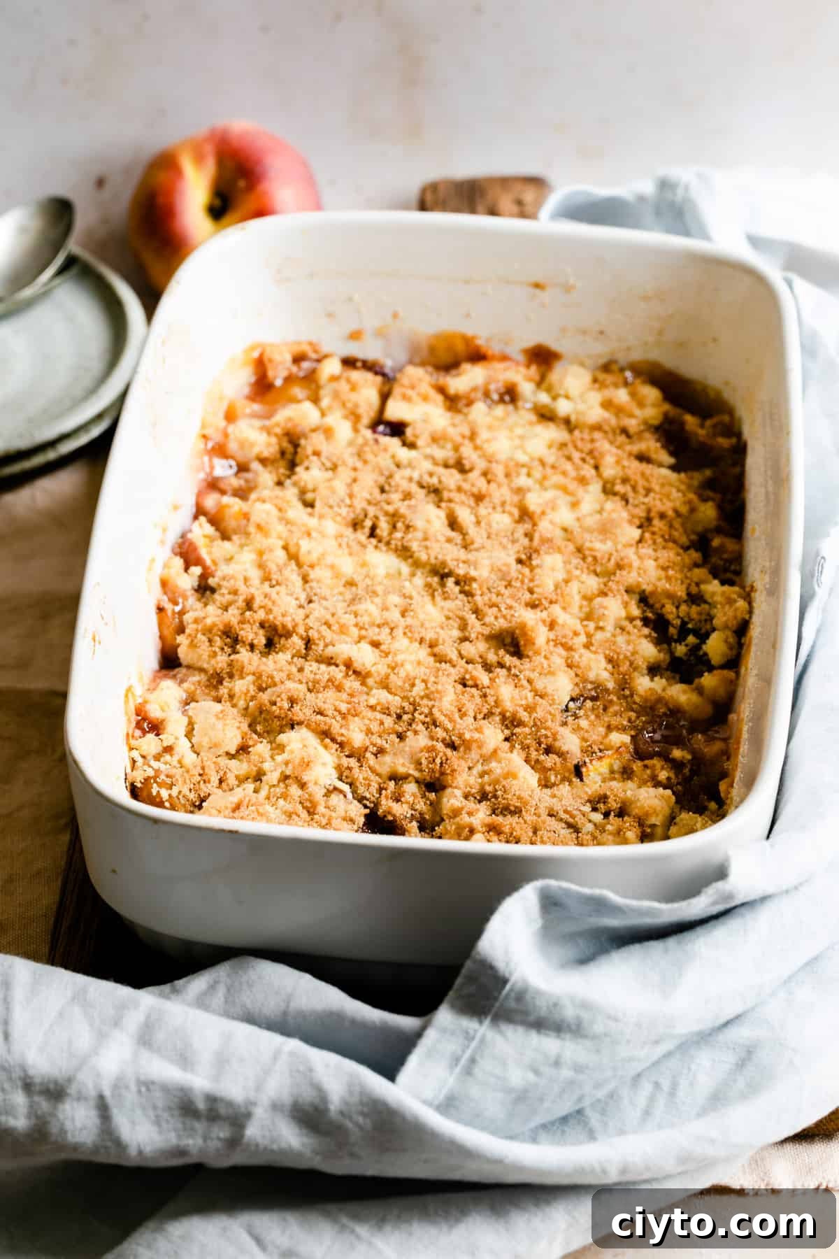 baked peach cobbler in a white baking dish