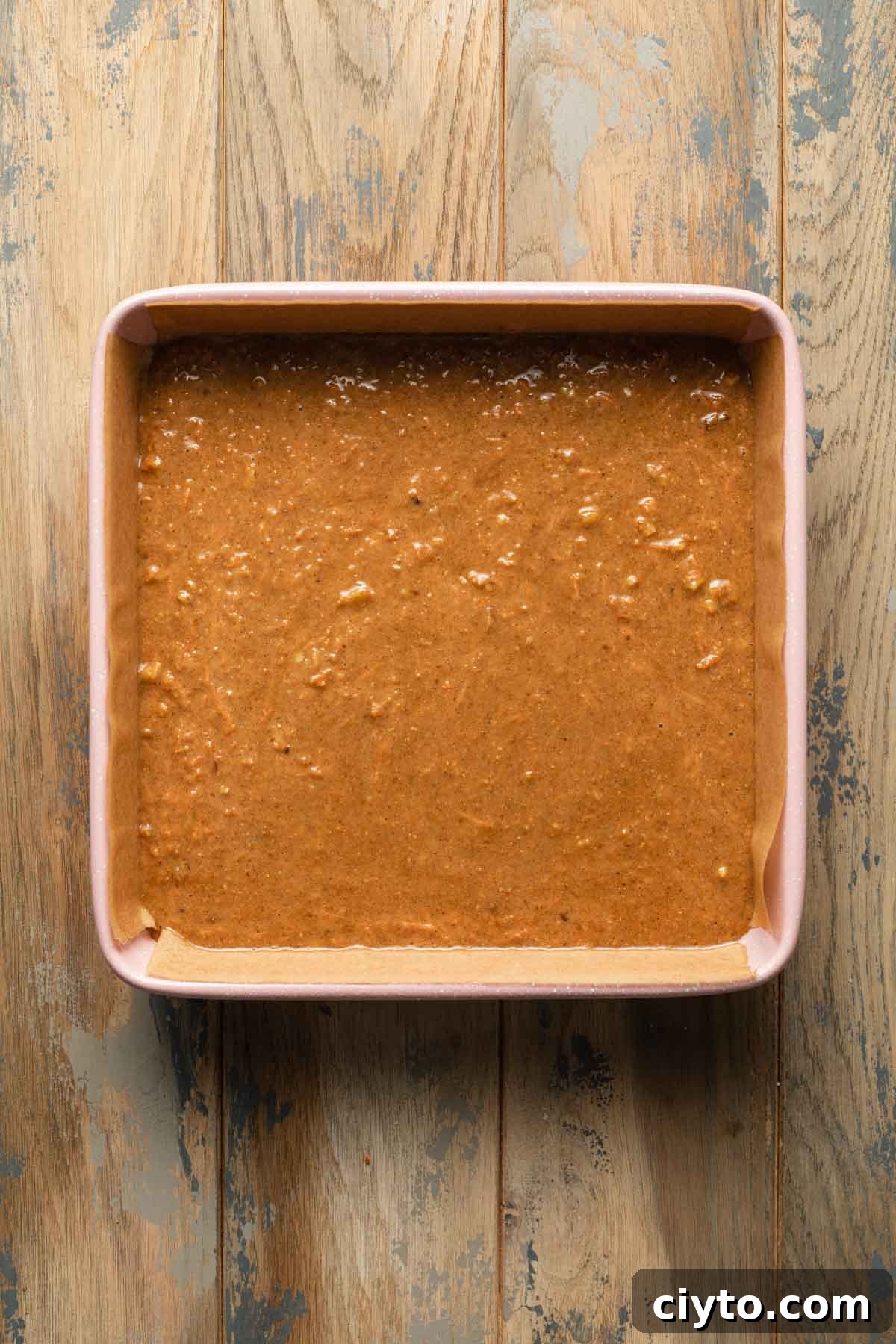 Carrot cake batter in a pink square baking pan.