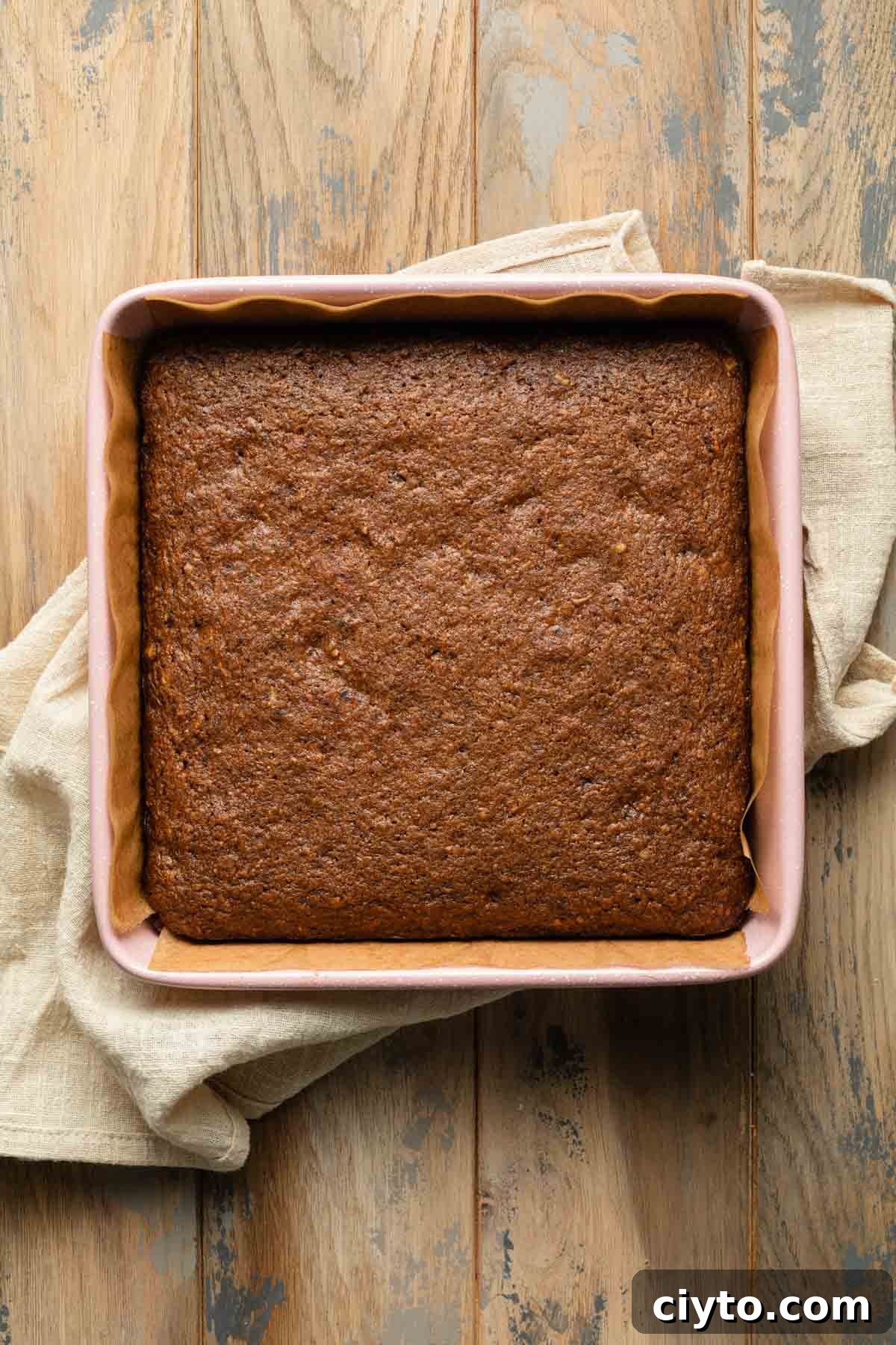 Carrot cake cooling in a pink square baking pan.