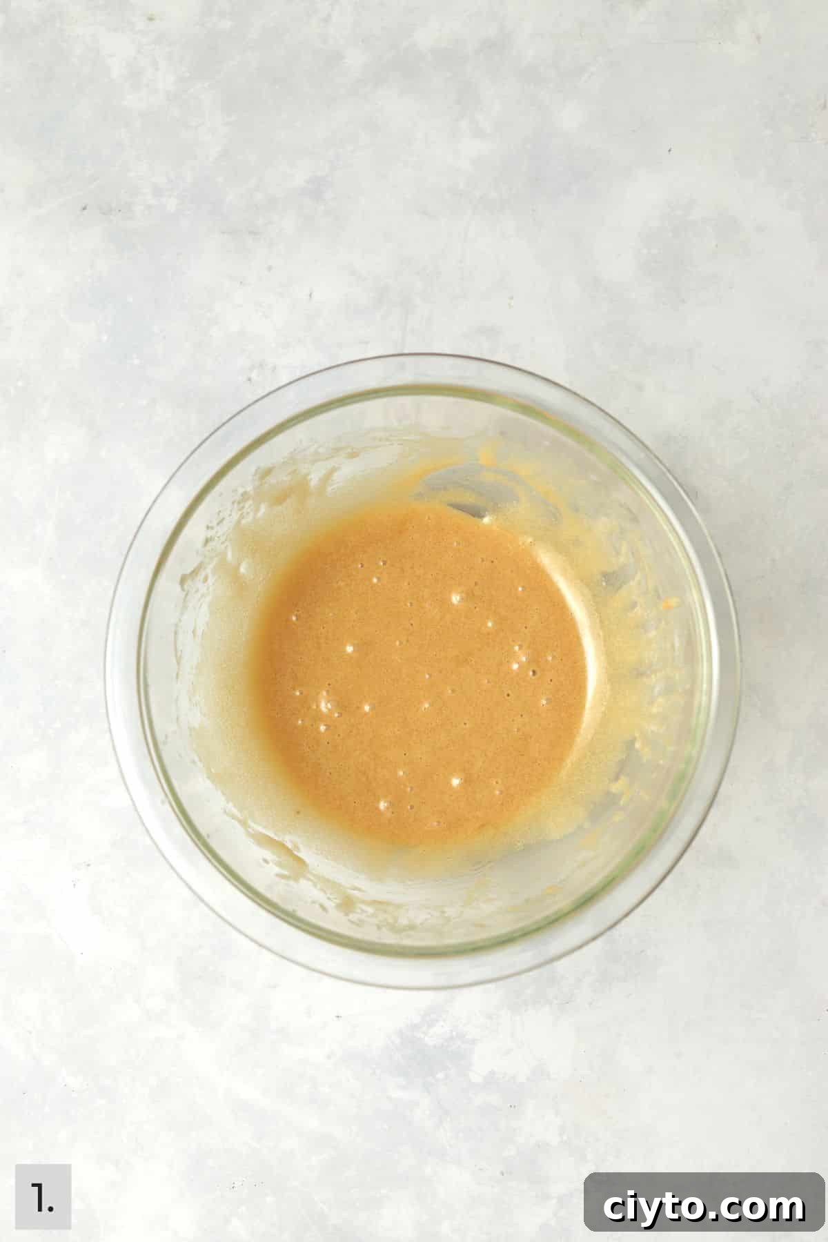 Butter, sugar, egg yolk, and vanilla mixed together in a glass bowl.