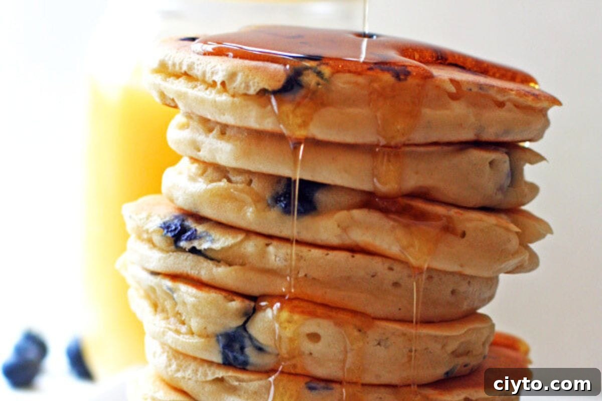 A stack of blueberry pancakes dripping in syrup.
