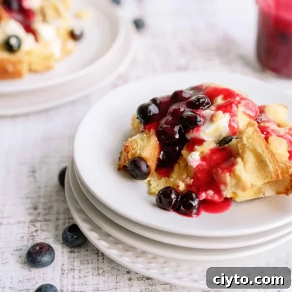 A slice of Overnight Blueberry French Toast on a plate with fresh blueberries.