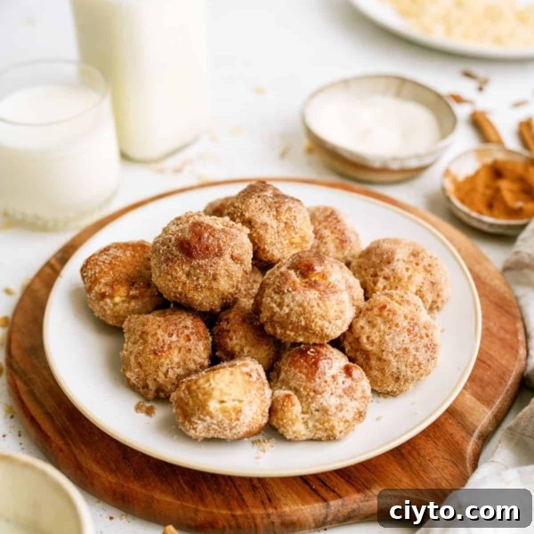 Cinnamon breakfast bites stacked on a plate with a cutting board underneath. A glass of milk and a bottle of milk on the side.