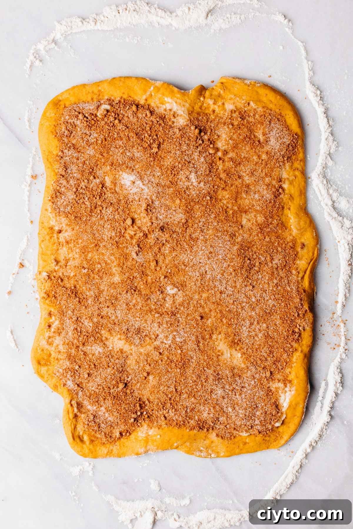 Butter and cinnamon sugar spread on rolled dough.