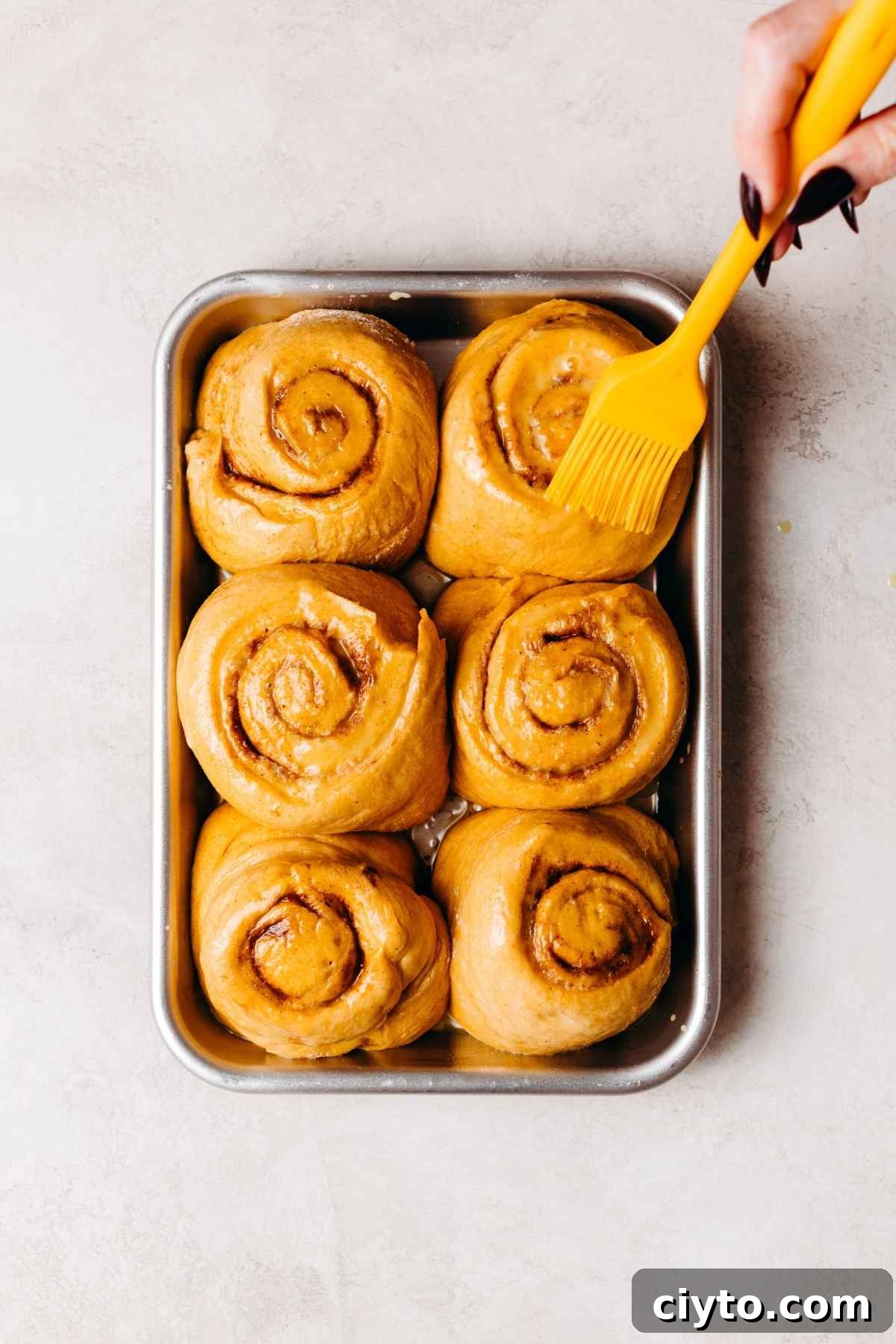 Egg wash brushed onto rolls on a baking sheet.