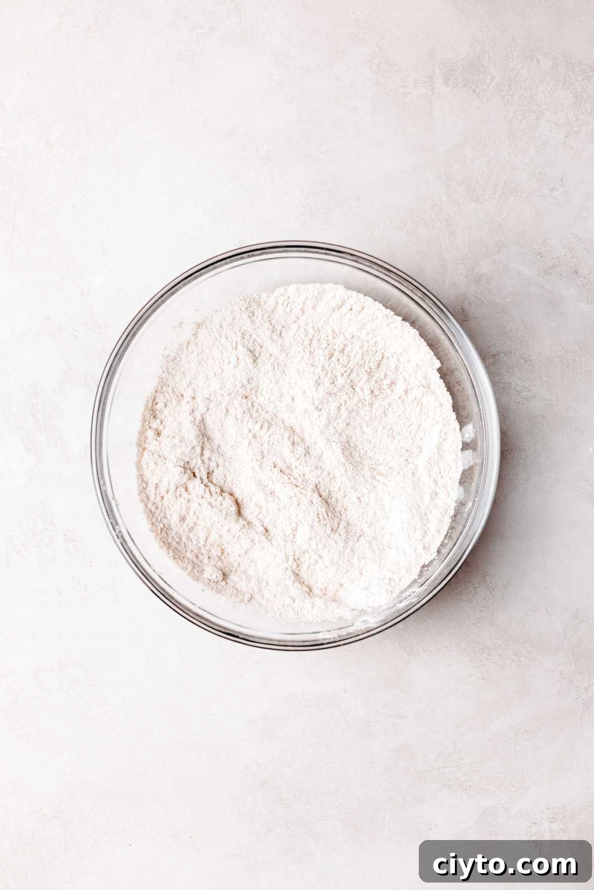 Whisked flour, yeast, brown sugar, cinnamon, and salt in a glass bowl.