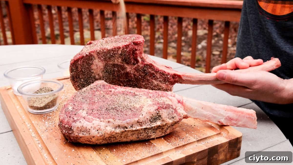 Seasoning ribeye steaks with salt, pepper, garlic on cutting board.