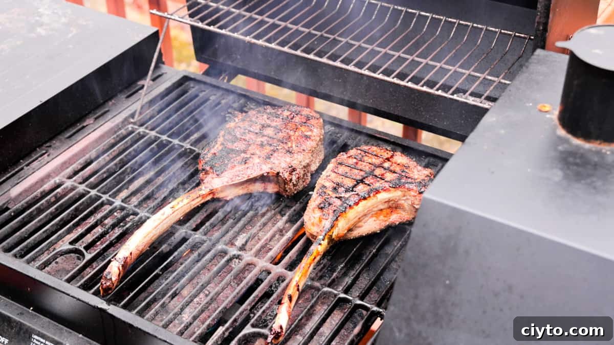 Ribeye steaks on grill cooking with a little smoke.