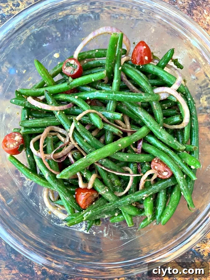 cold green bean salad with tomatoes and feta cheese in a glass bowl