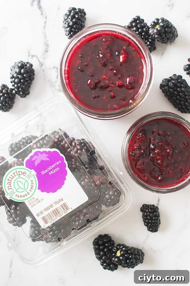 overhead shot of blackberry jam in mason jars with blackberries scattered