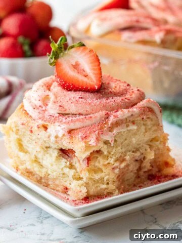 Baked strawberry cheesecake cinnamon roll on white plate.