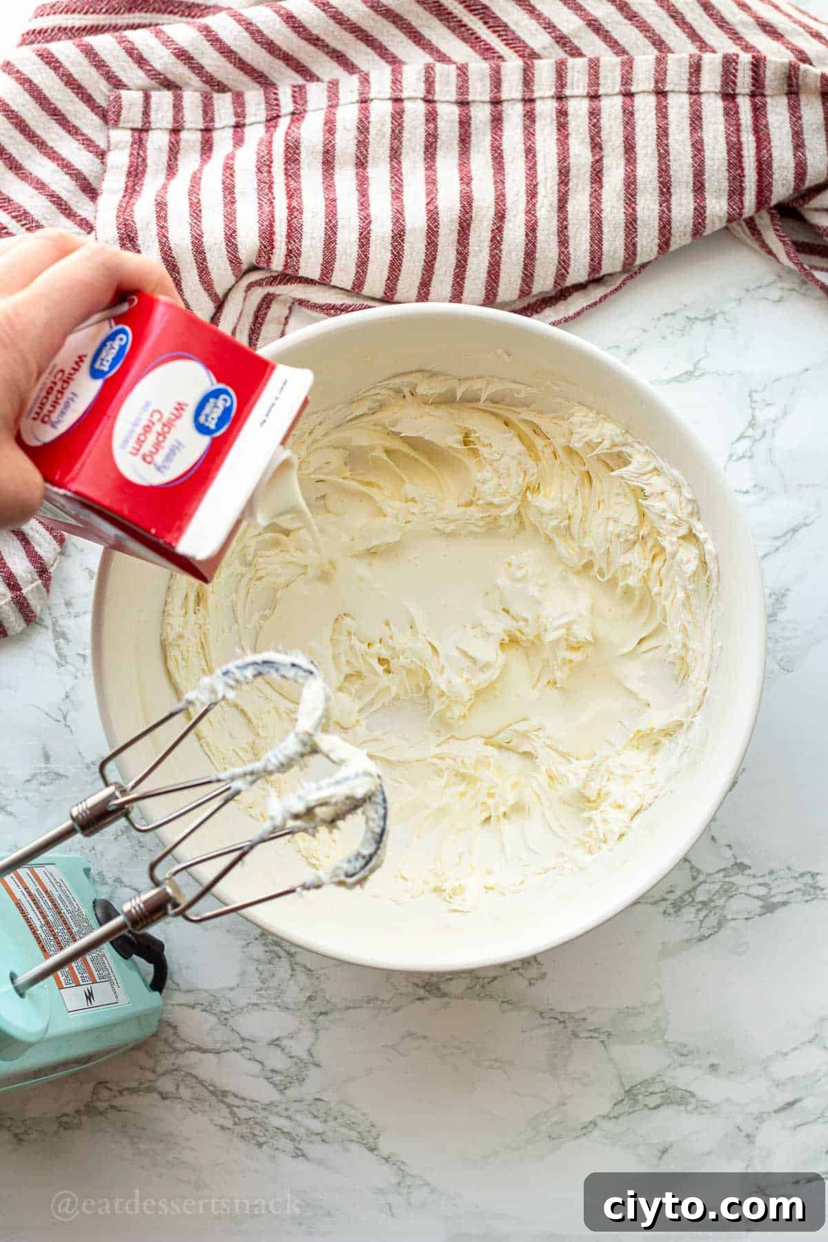 Pouring cream into whipped cream cheese in bowl.
