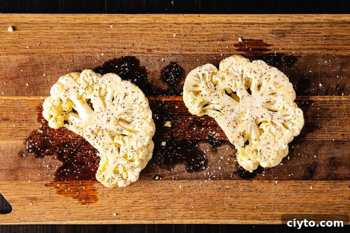 Cauliflower steaks on a cutting board drizzled with oil.