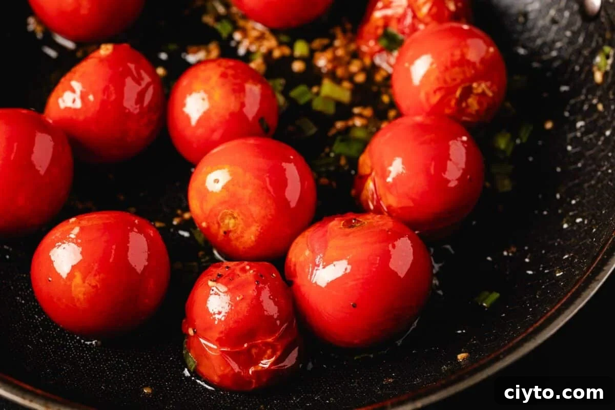Tomatoes cooking in a cast iron skillet.