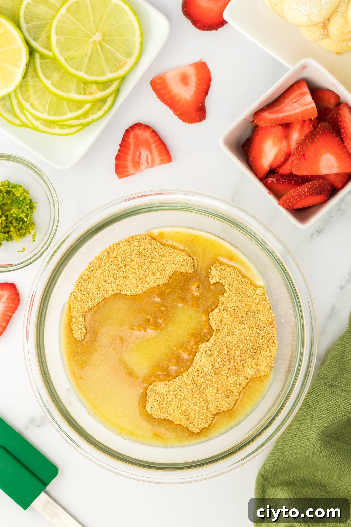 Top-down view of melted butter with graham cracker crumbs in mixing bowl.