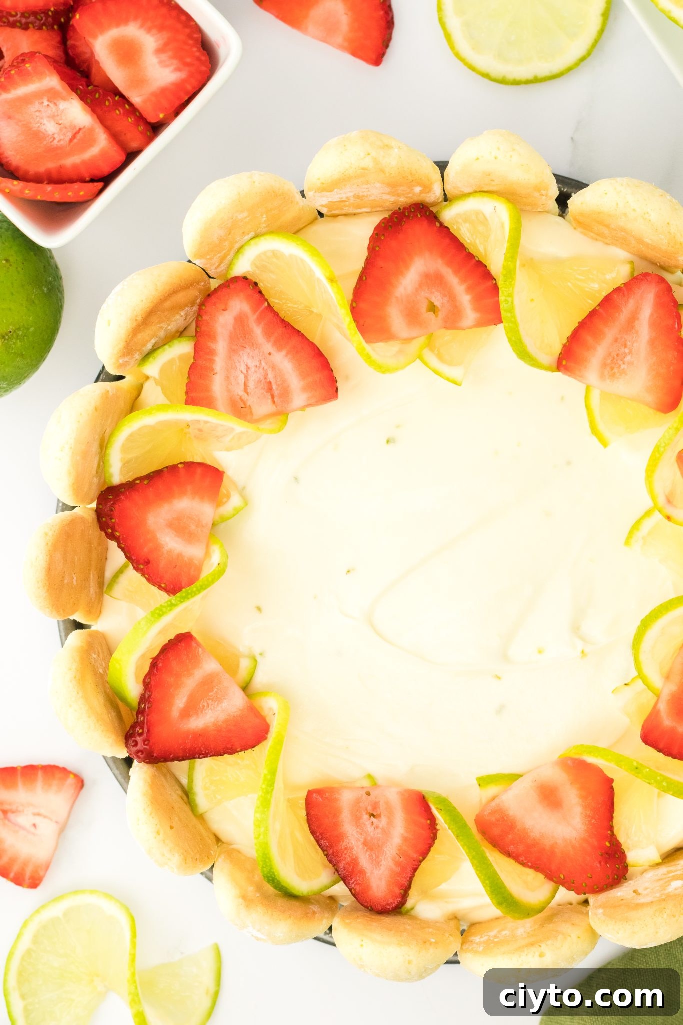 Top down close up of no bake lime cheesecake topped with strawberries and lime slices.