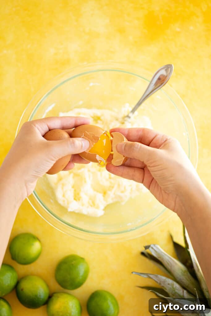 Moist Pina Colada Cake Recipe with Fresh Pineapple 4 eggs cracking into a bowl