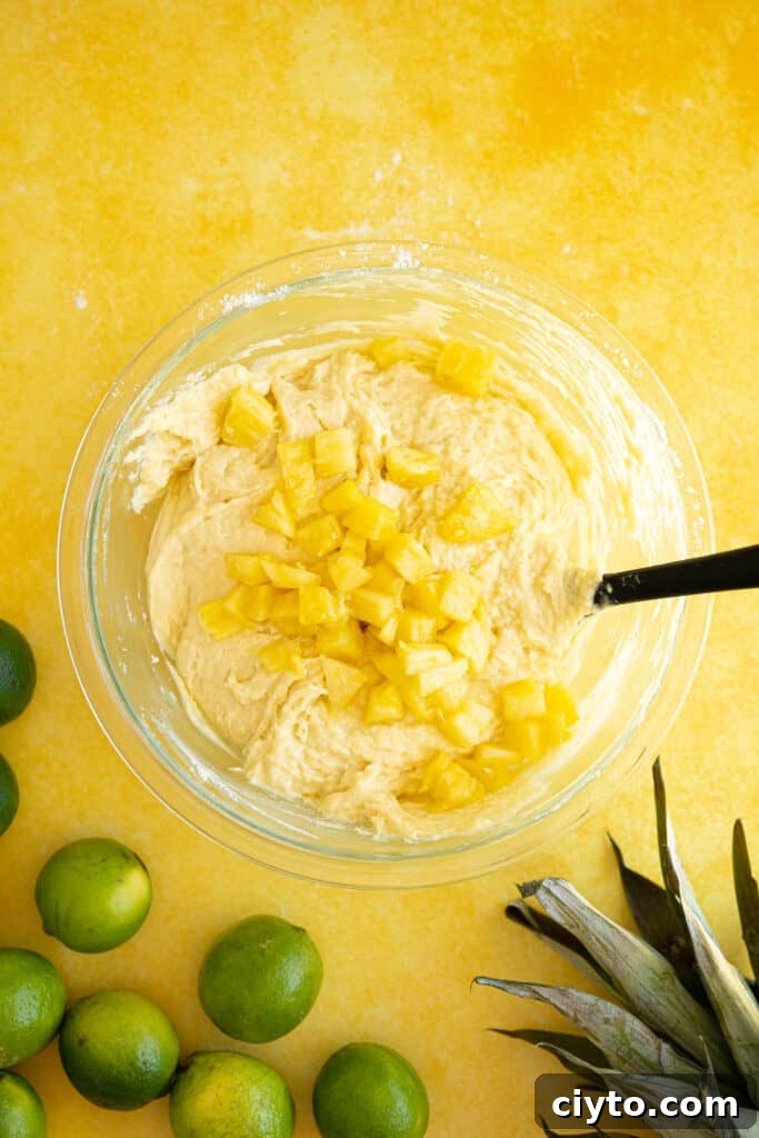 Moist Pina Colada Cake Recipe with Fresh Pineapple 6 pineapple chunks in a bowl of cake batter