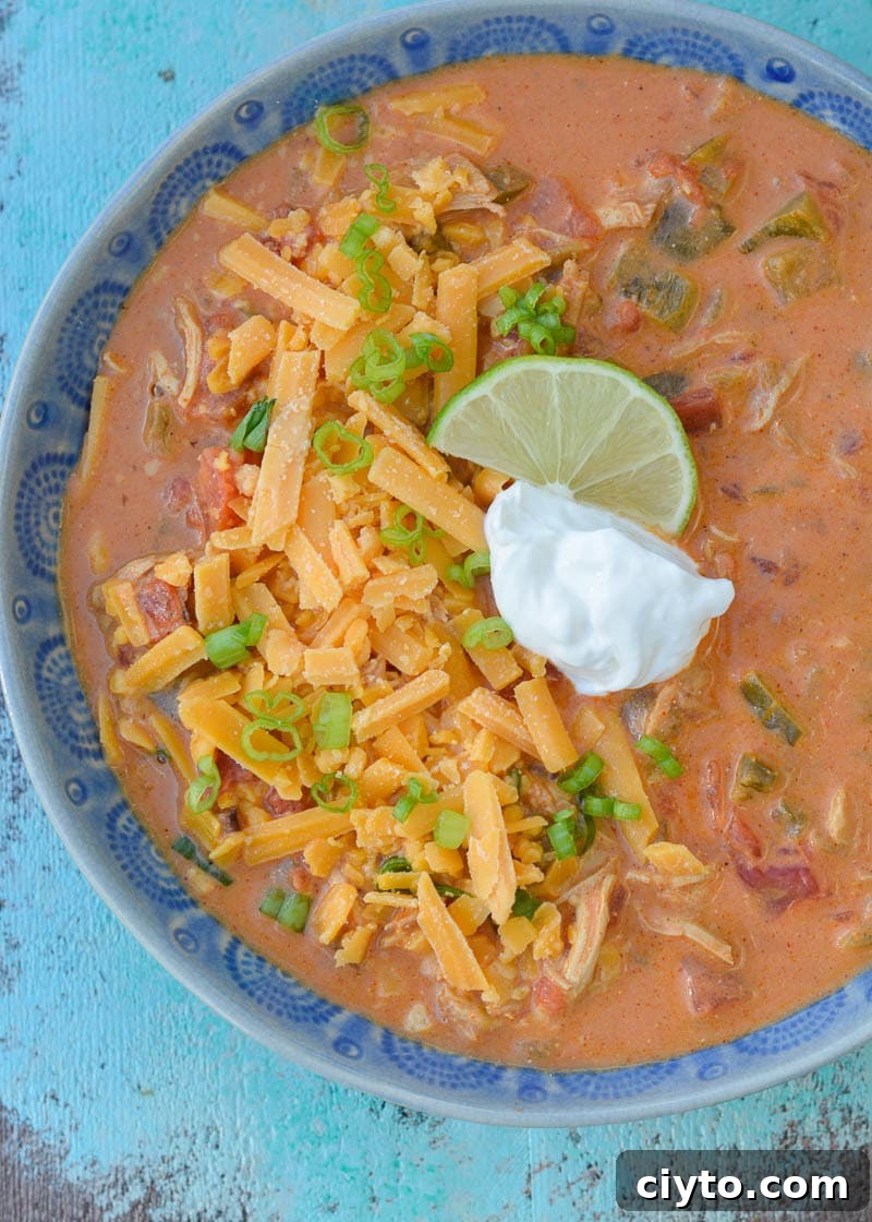 This Keto Cheesy Chicken Enchilada Soup has just about 6 net carbs and is super creamy! Top with shredded cheese, sour cream, green onions, and a squeeze of lime to bring it over the top!