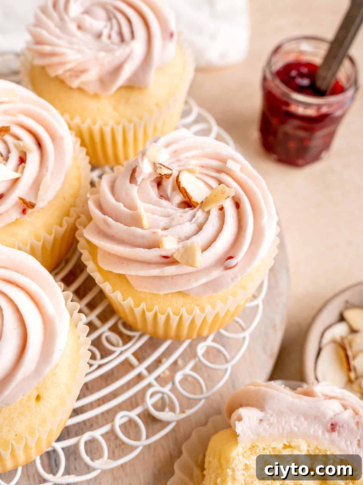 Almond cupcakes with raspberry frosting and sliced almonds on top.