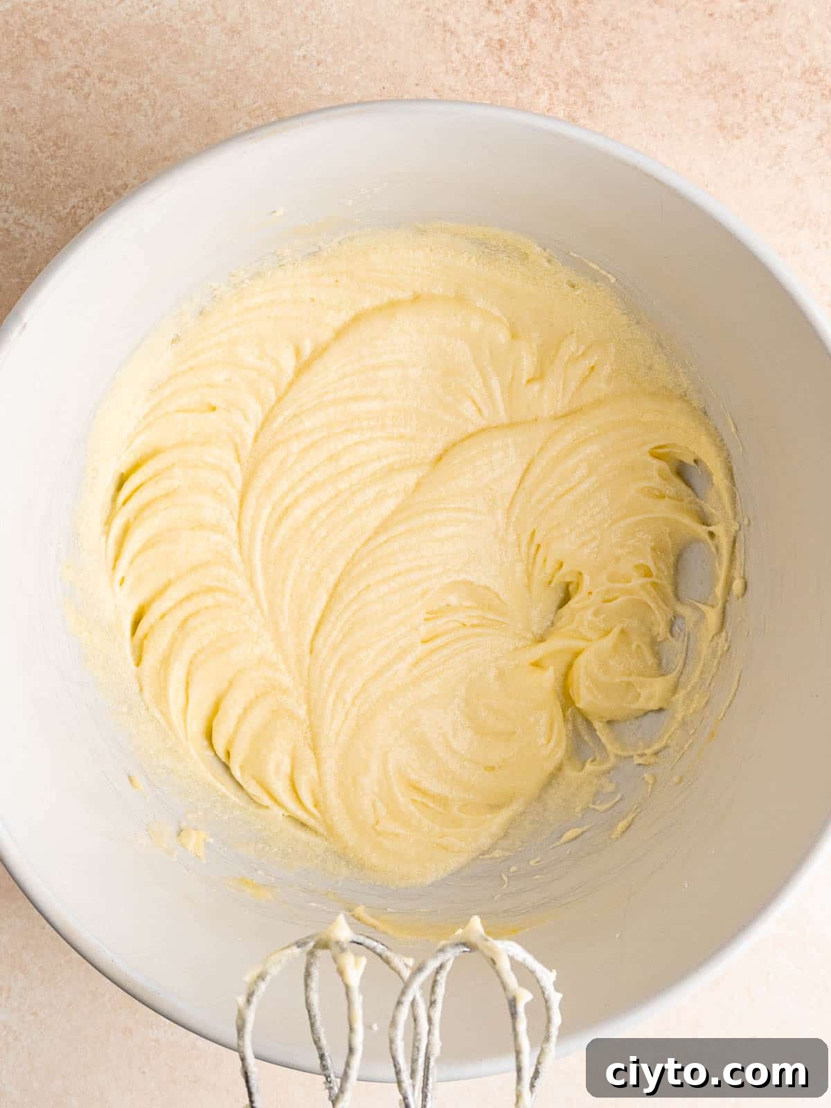 Butter, sugar, eggs, almond extract and sour cream mixed together in a bowl.