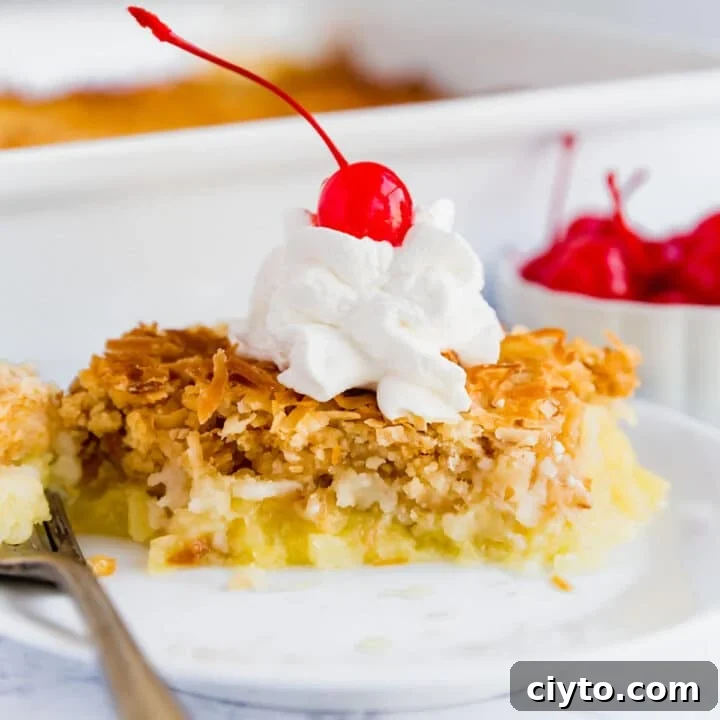A close up image of Piña Colada dump cake on a plate with whipped cream and a cherry on top.