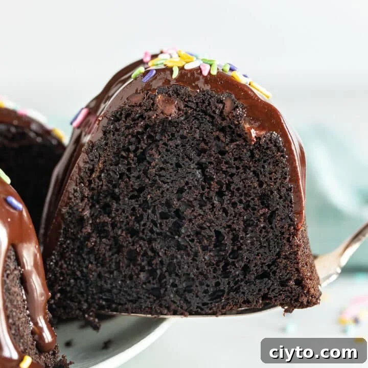 A piece of chocolate cake being pulled from the whole cake revealing the moist inside.