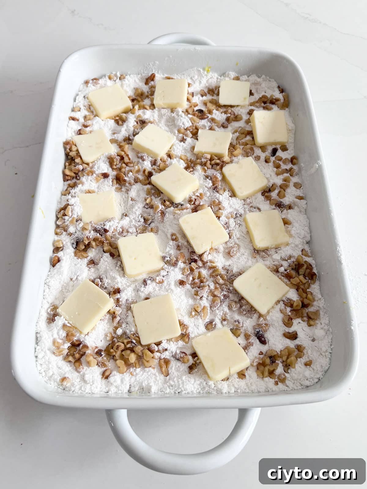 Dump cake in baking dish with pats of butter spread along the top and ready to be put into the oven.