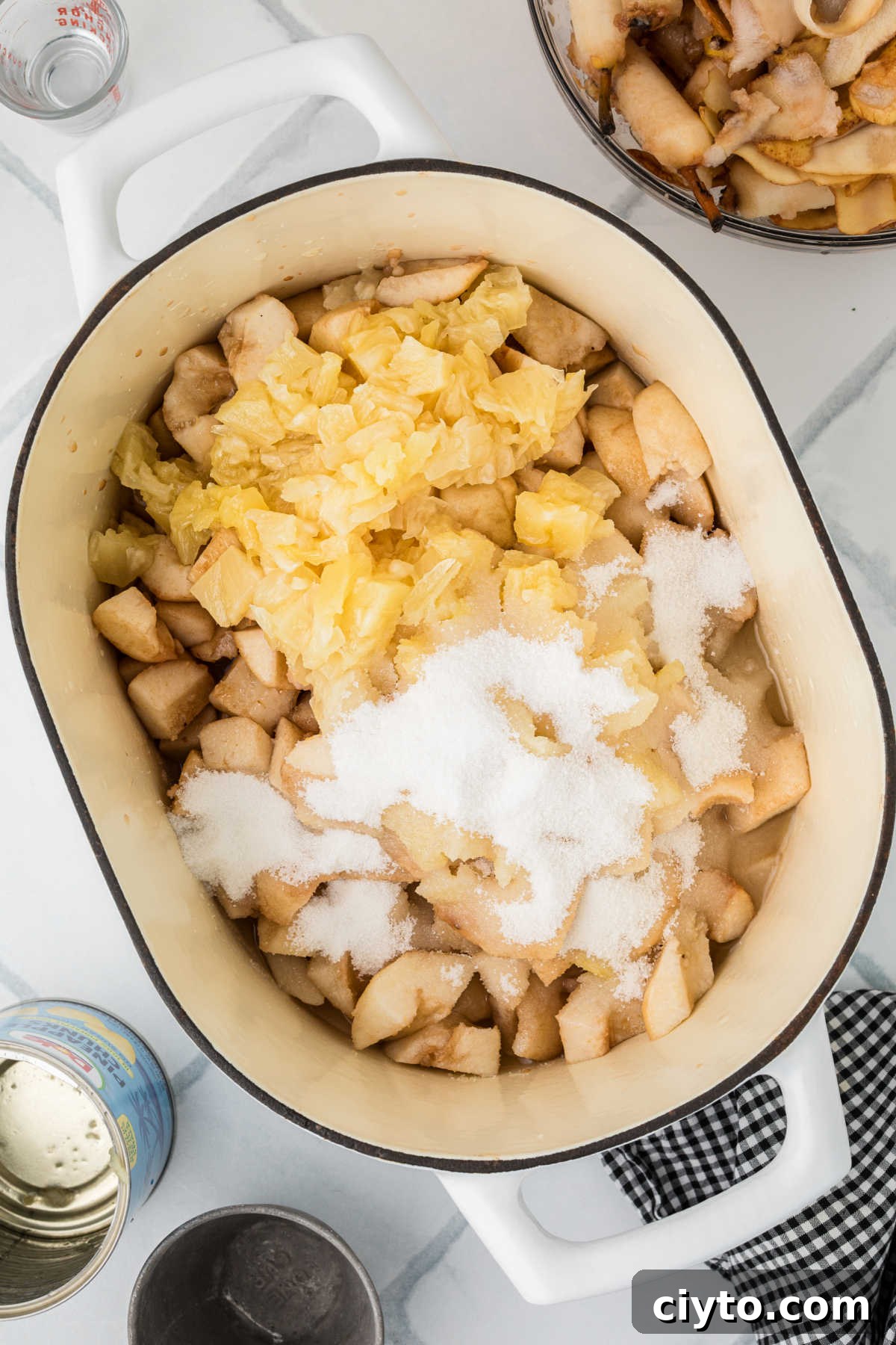 A large heavy bottomed pot with some chopped pears, sugar, crushed pineapple and lemon juice.