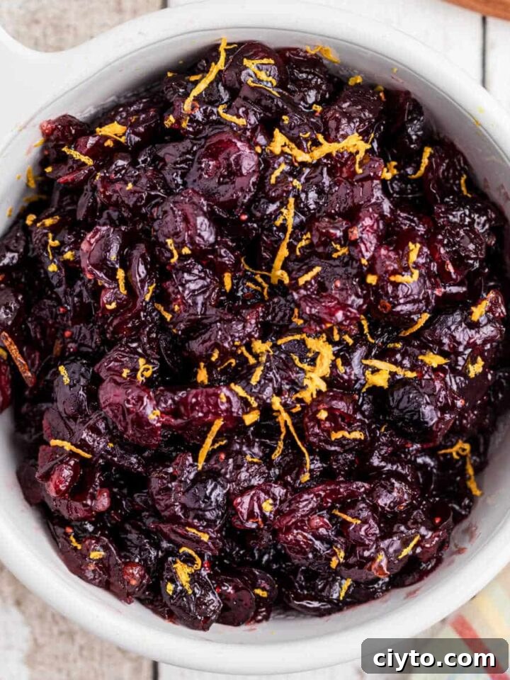 close up overhead image of a bowl of dried cranberry sauce with some orange zest sprinkled on top.