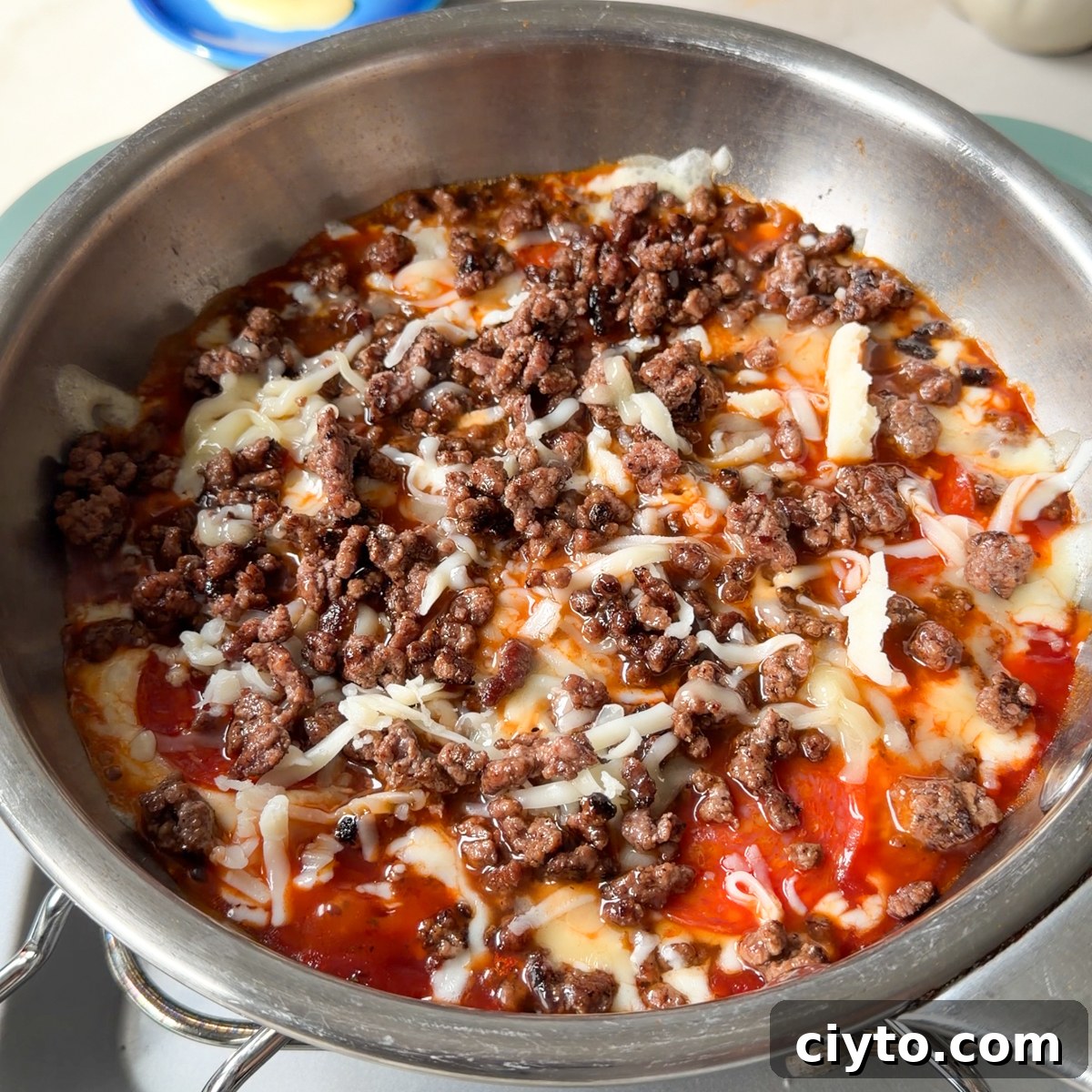 Add the tomato sauce, cheese, pepperoni and beef to a small skillet over low heat