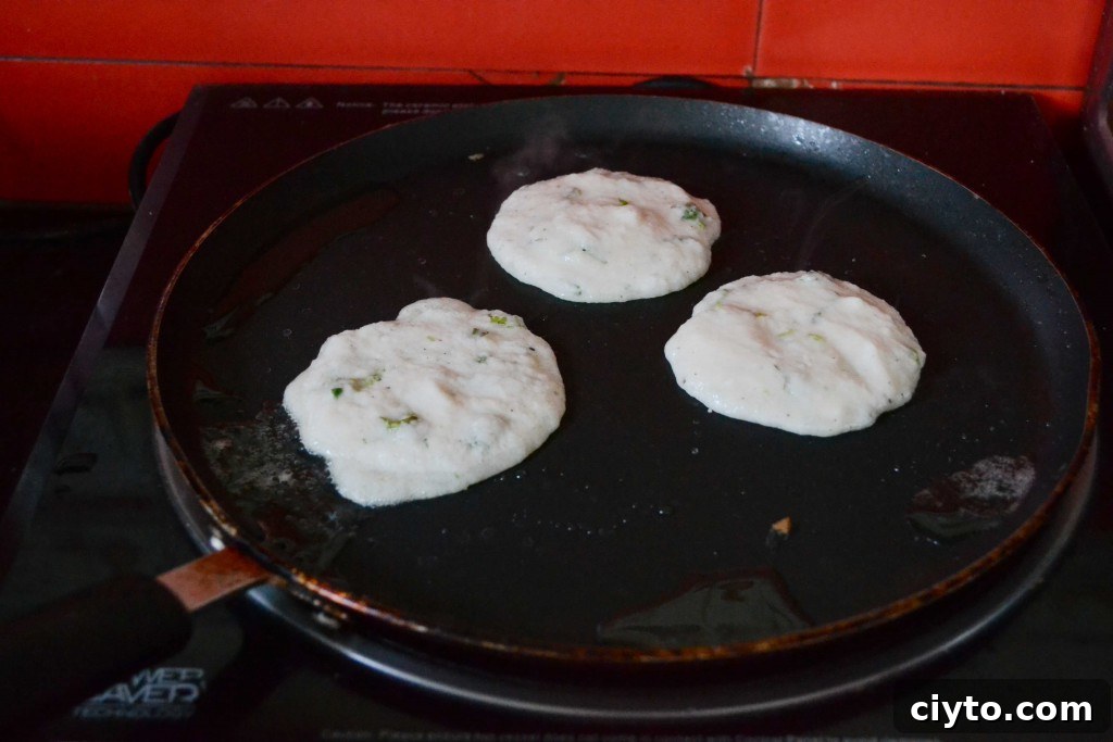 Hand holding a potato pancake topped with sour cream
