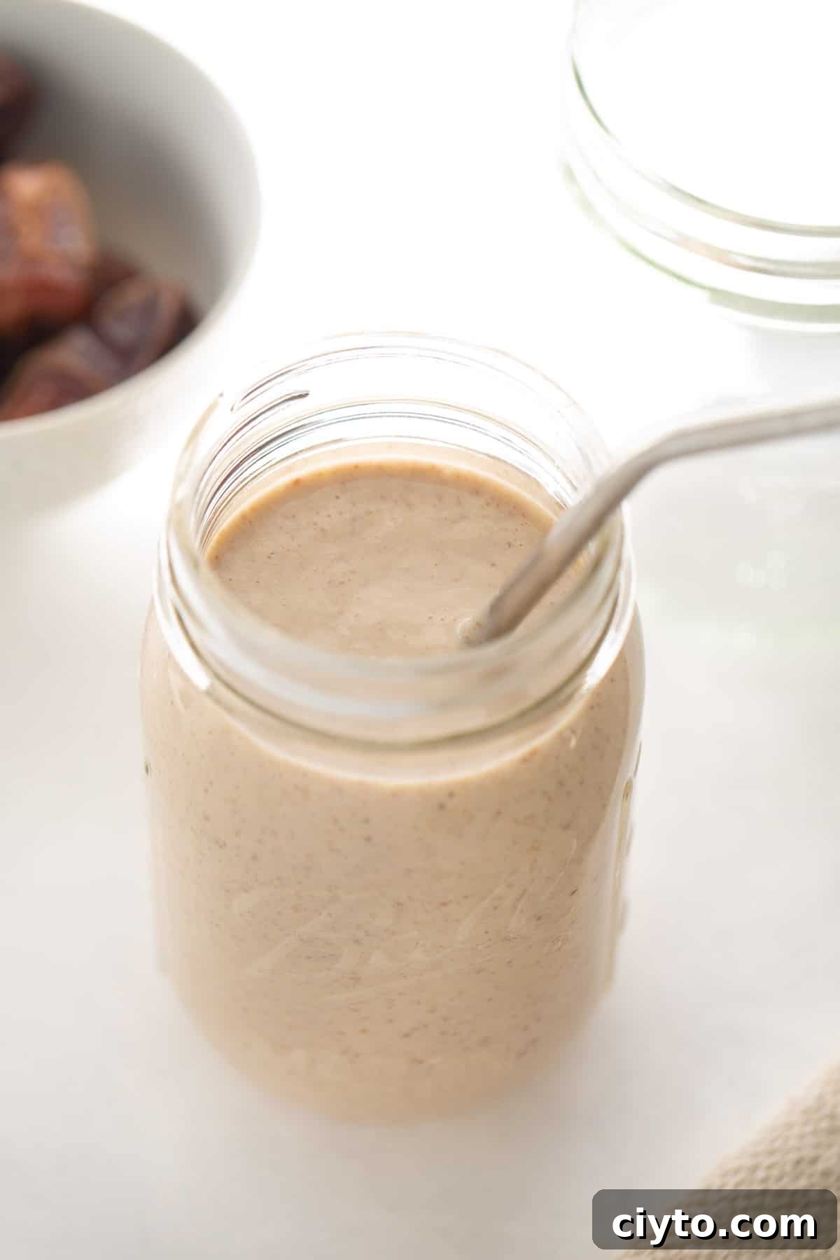 date and banana smoothie in a tall glass with straw