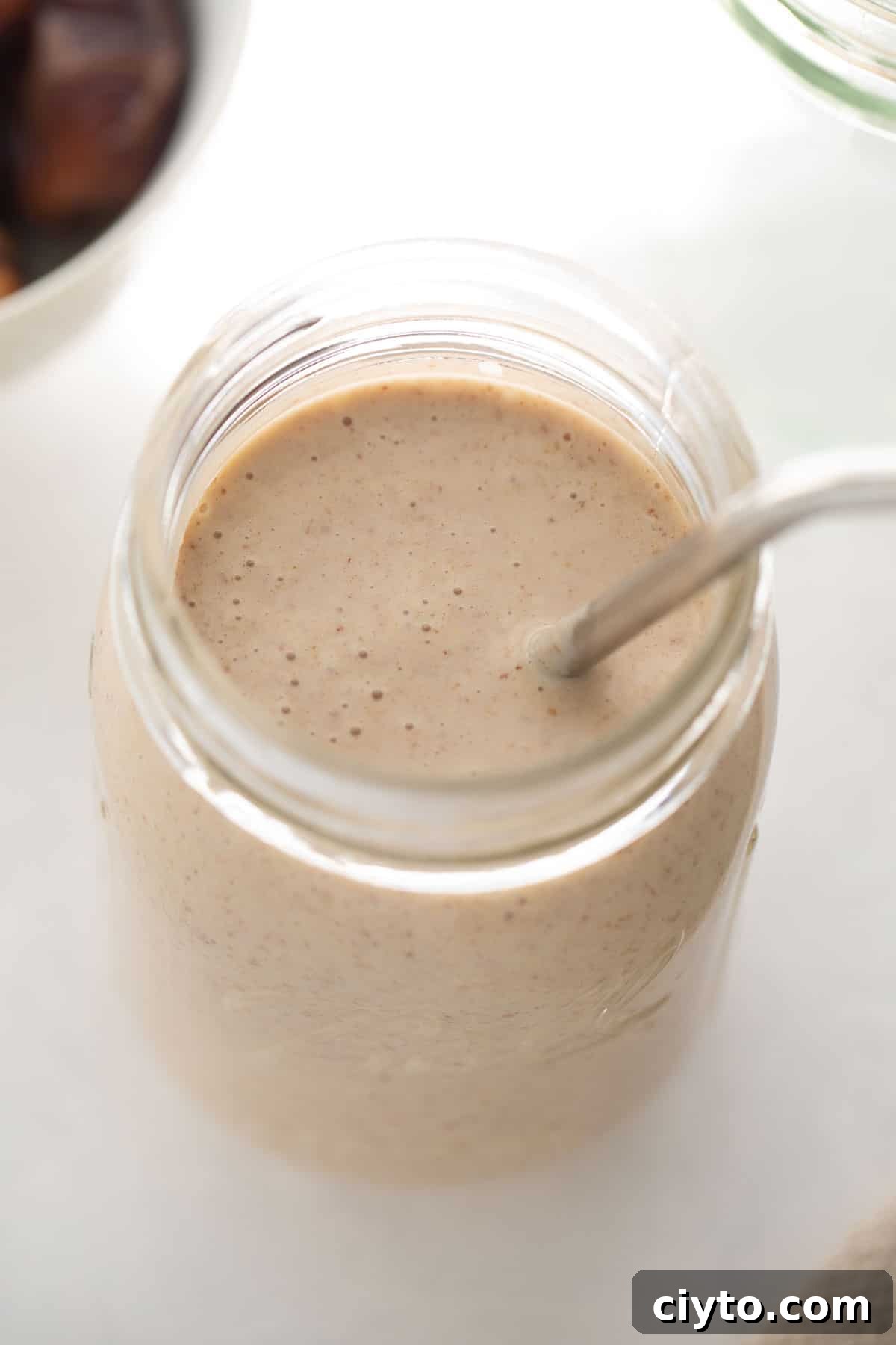healthy banana smoothie in a glass with straw
