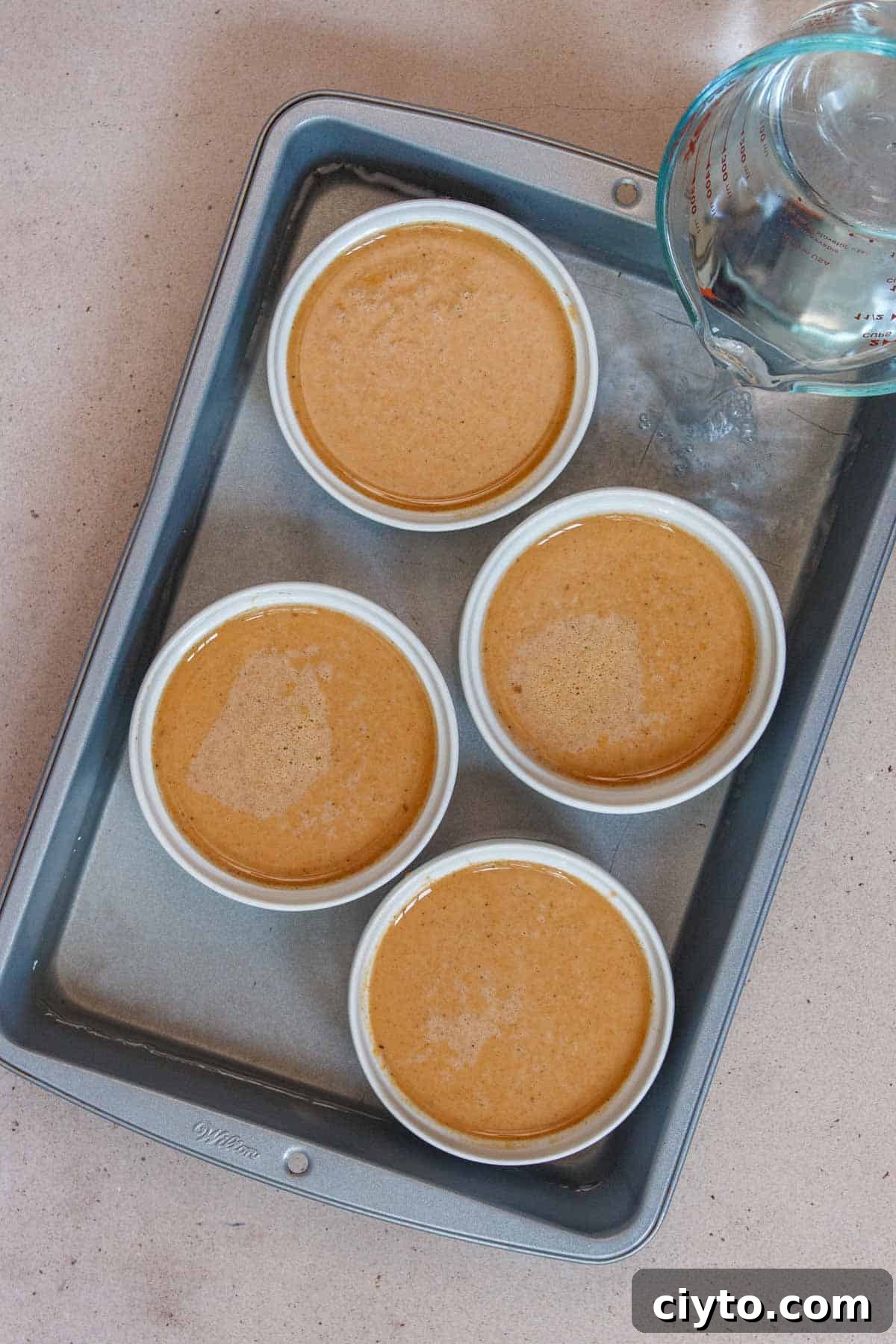 Pumpkin custard ramekins in a water bath.