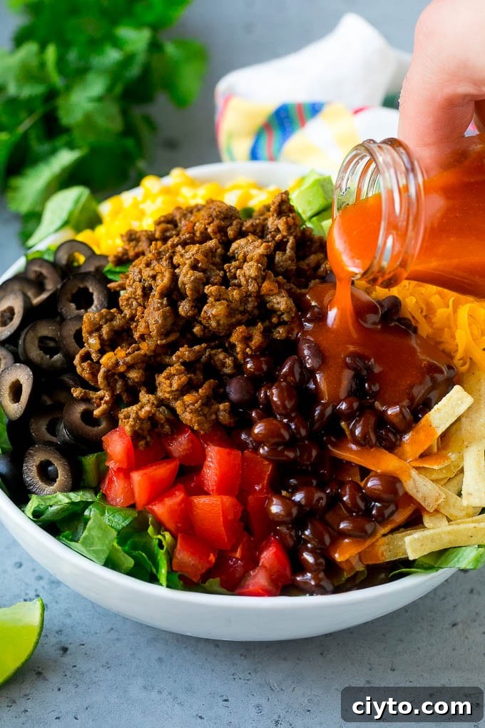 Crispy Taco Salad with Fresh Salsa and Avocado 6 Catalina dressing being poured over taco salad.